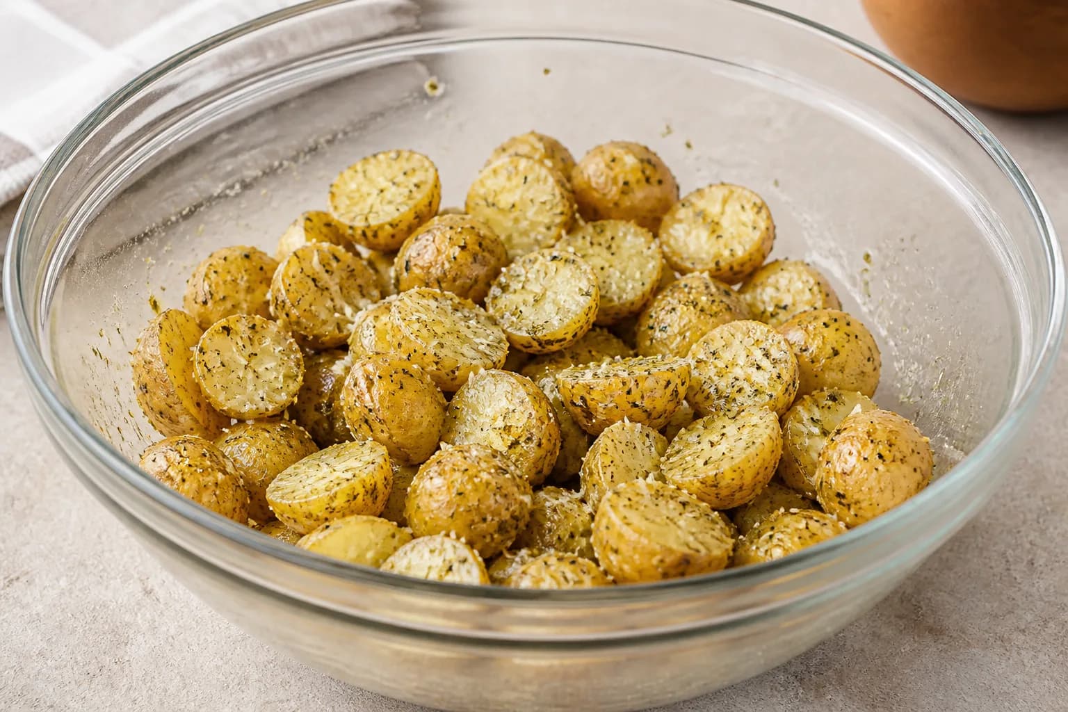 Crispy Air Fryer Garlic Parmesan Baby Potatoes after step 2: Pat the cut potatoes dry with a clean towel. In a large bowl, toss them with the olive oil, garlic powder, Italian seasoning, salt, pepper, and 15 g of the Par